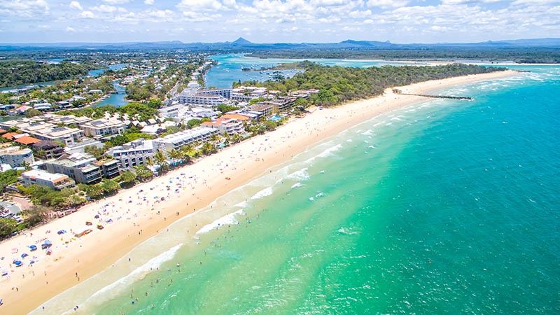 An aerial view of Noosa on Queensland's Sunshine Coast, including beach and leafy suburbia and inlet.