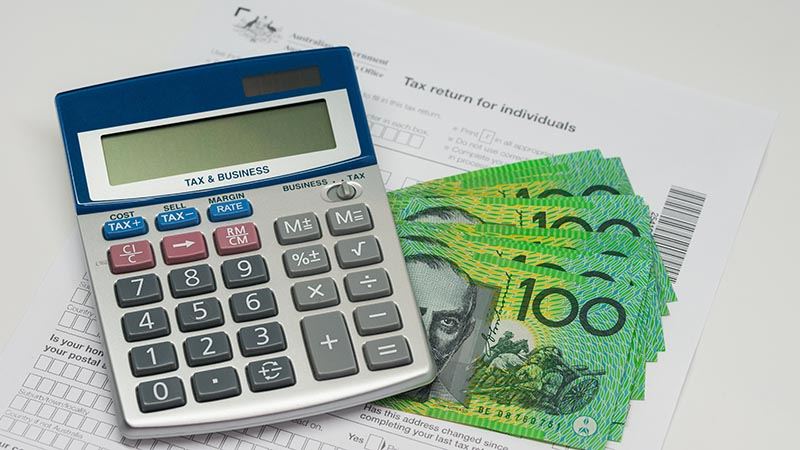 Australian $100 notes and calculator on tax return form