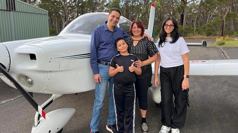 Anna and Melvyn Correia and their children stand beside light aircraft.