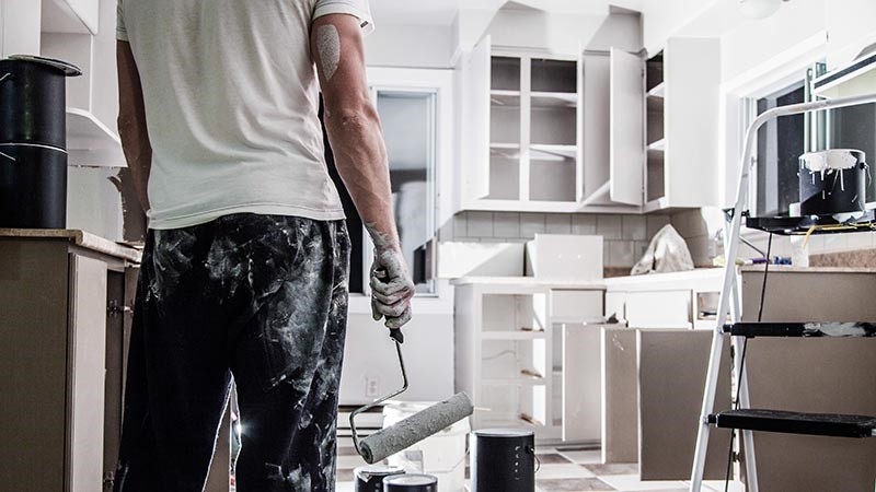 Man renovating kitchen, with paint cans in background